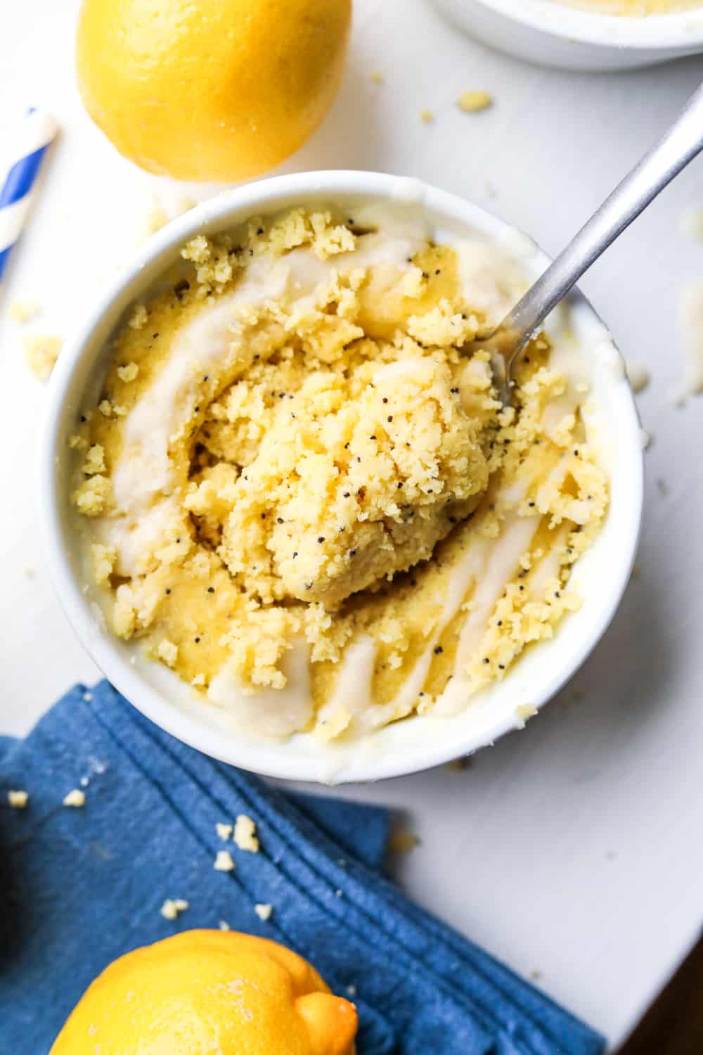 A fork about to take a piece of lemon cake from a mug full of cake.