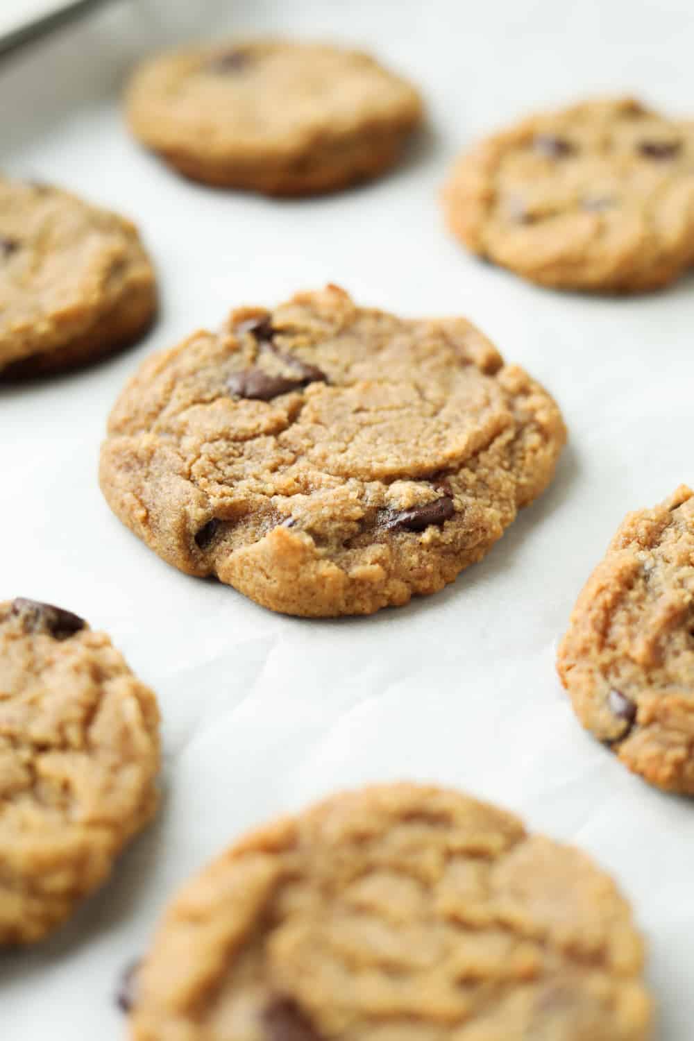 Chocolate chip cookie on a baking sheet lined with parchment paper.