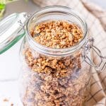 Granola in a glass jar on a white table.