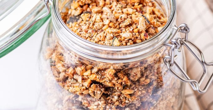 Granola in a glass jar on a white table.