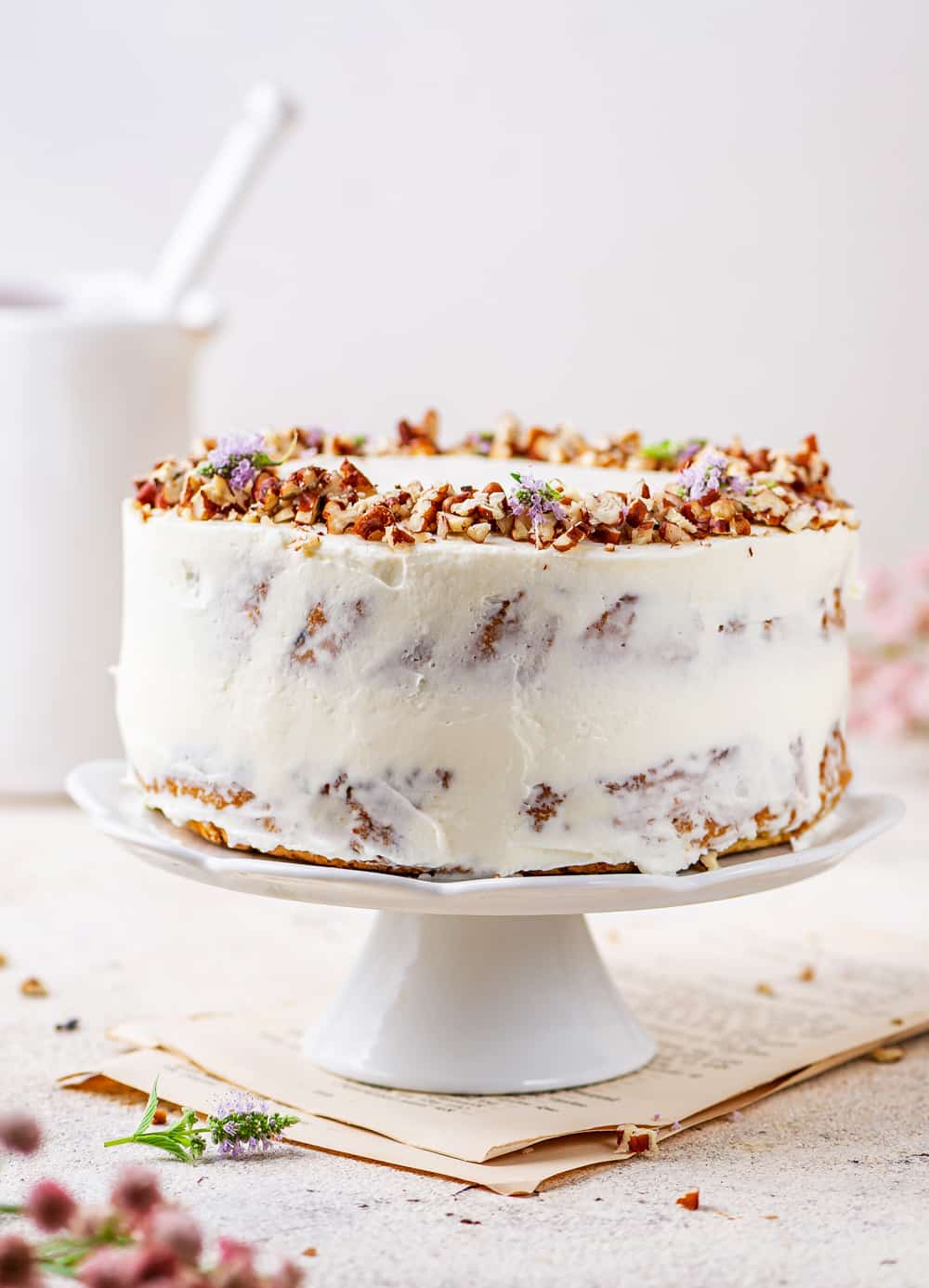 Carrot Cake topped with pecans on a white serving tray.