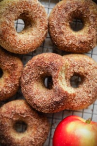 A bunch of donuts next to an apple.