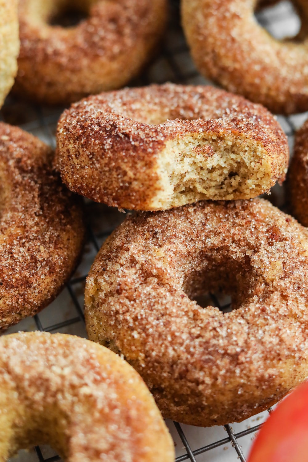 An apple cider donut with a bite taken out of it stacked on top of another donut.