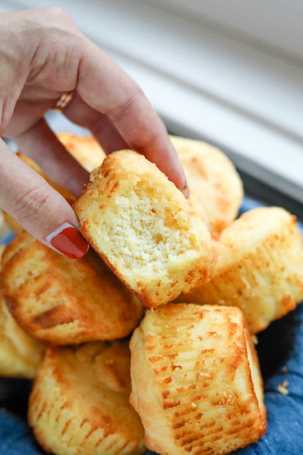 A hand holding a biscuit with a bite taken out of it.