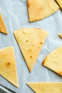 A bunch of tortilla chips on parchment paper.