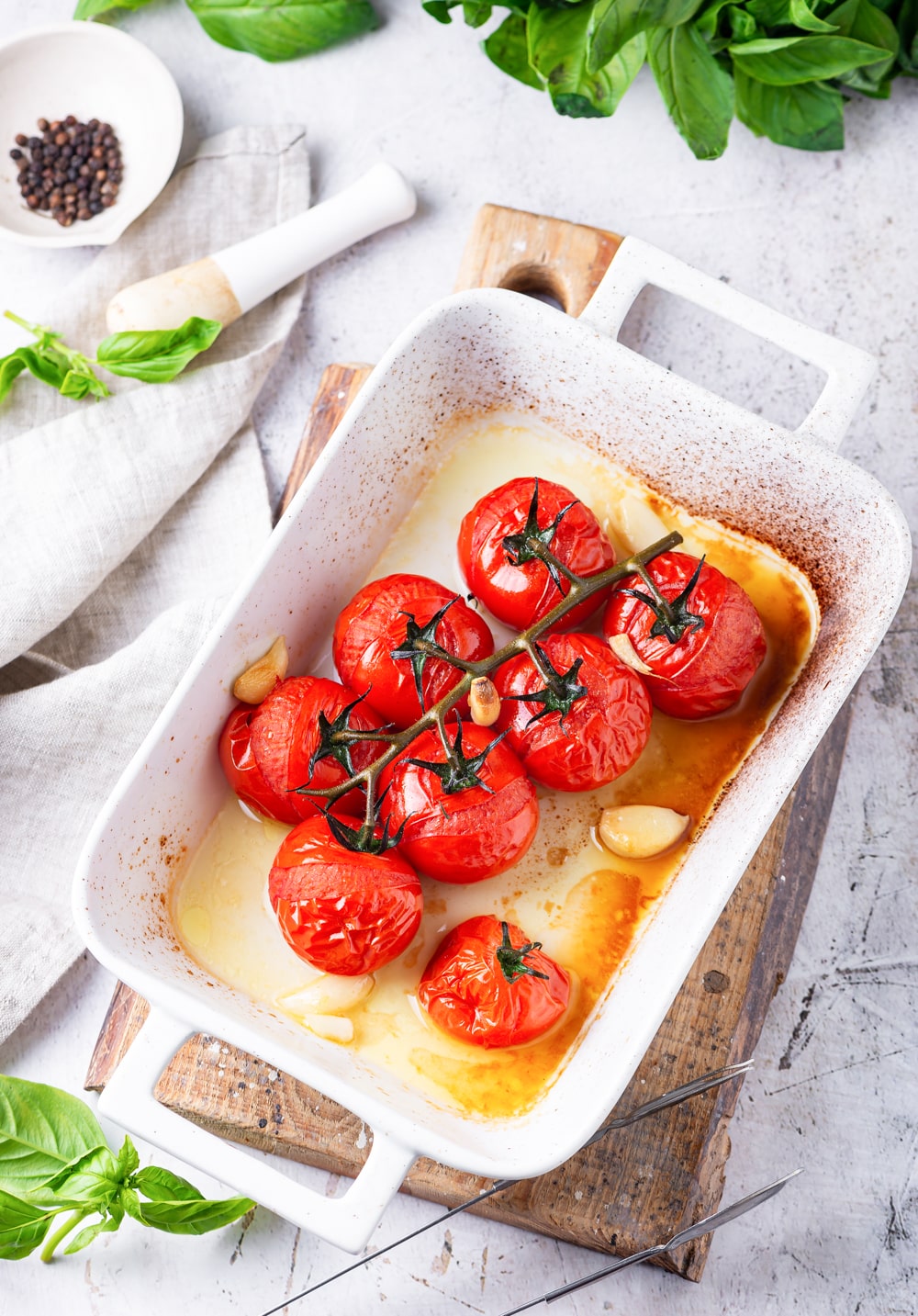 Tomatoes and garlic that have been cooked in a white baking dish.