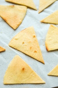 Tortilla chips on white parchment paper.