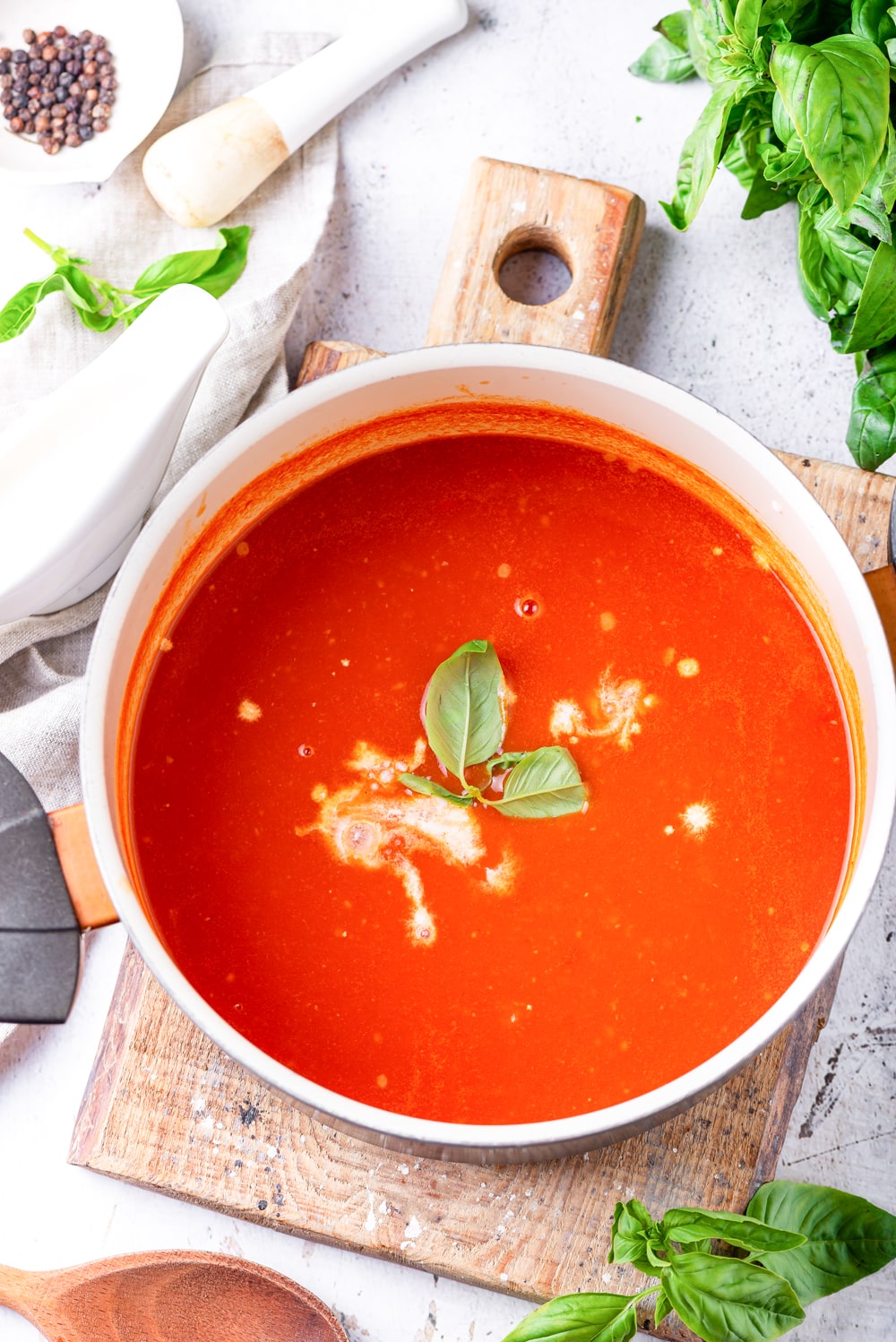 A pot of tomato soup on a cutting board.