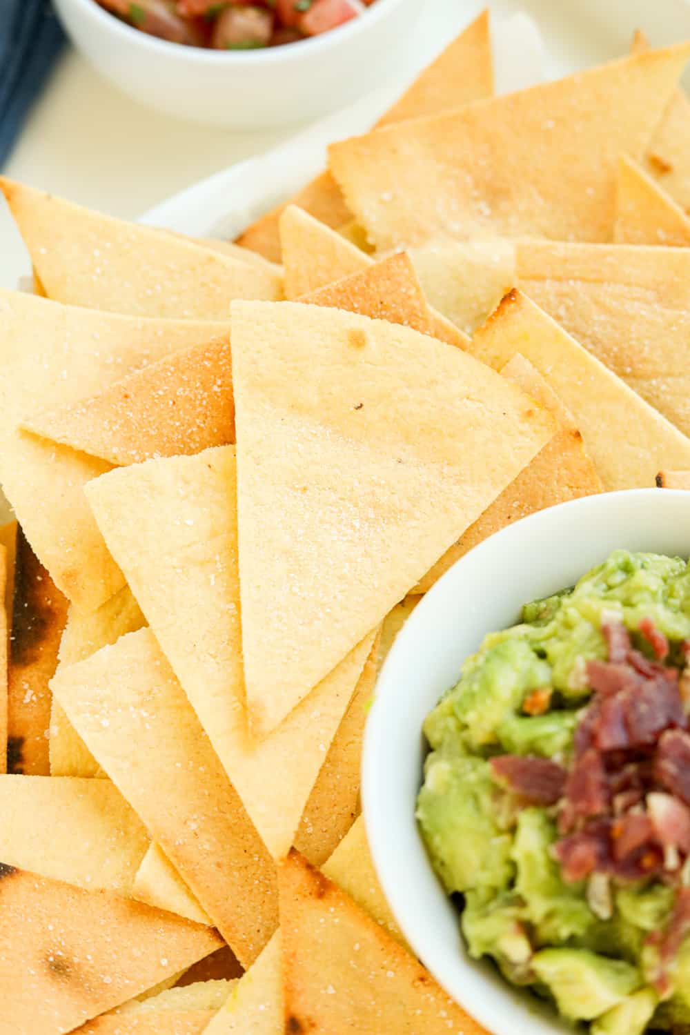 Tortilla chips stacked on top of one another next to guacamole.