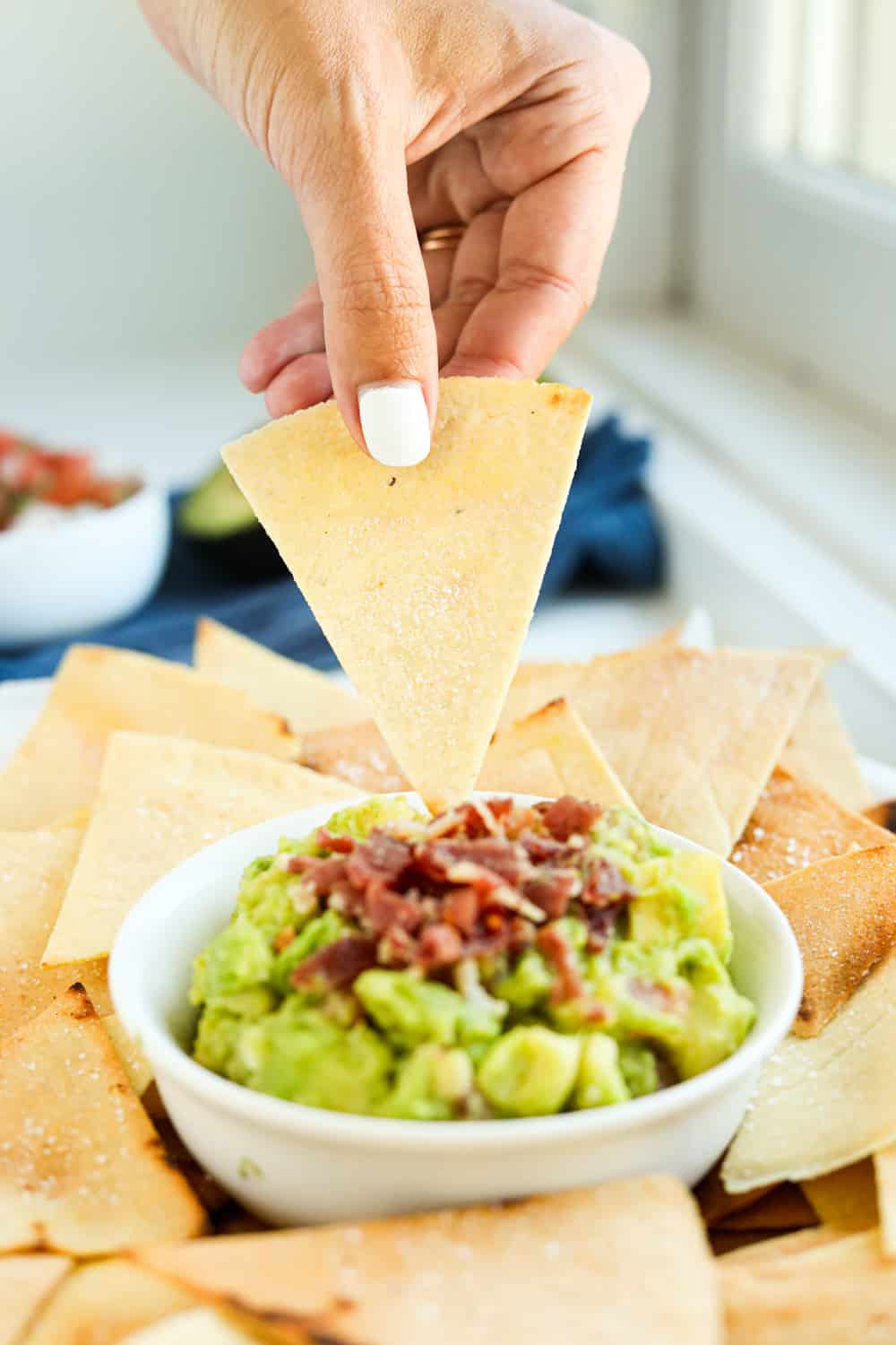 A tortilla chip just about to be dipped into guacamole.