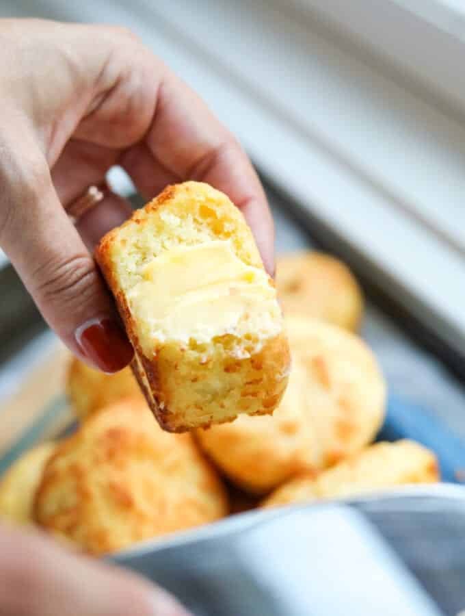 A biscuit that's been buttered being held in a hand.