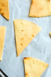 Tortilla chips on a baking sheet lined with parchment paper.