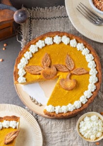 A pumpkin pie with a slice missing from it.