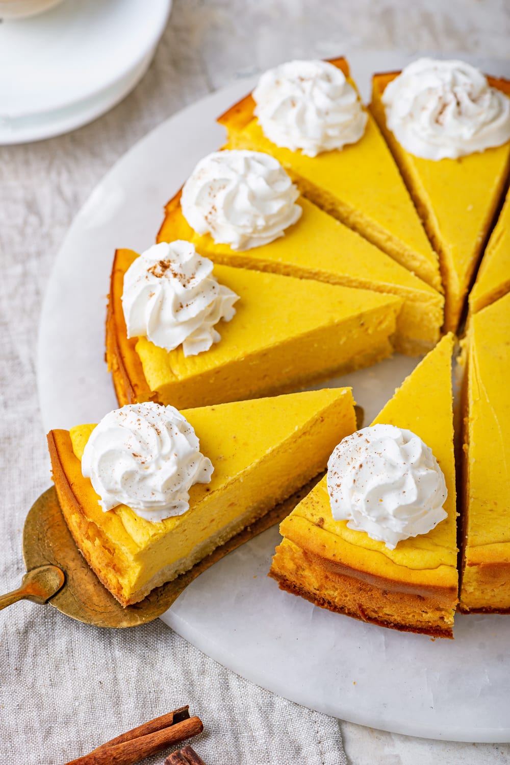 Slices of pumpkin cheesecake topped with whipped cream on a white plate.