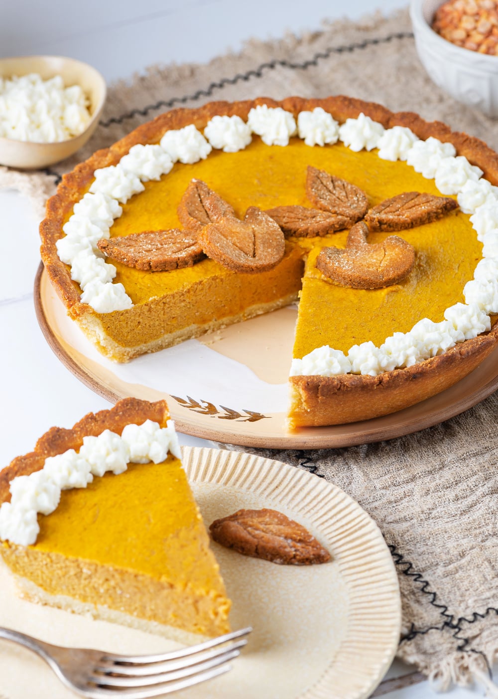 A slice of pumpkin pie set next to the rest of the pie.