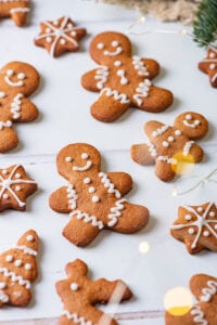 Gingerbread cookies on a white table with gold lights to the right of them.