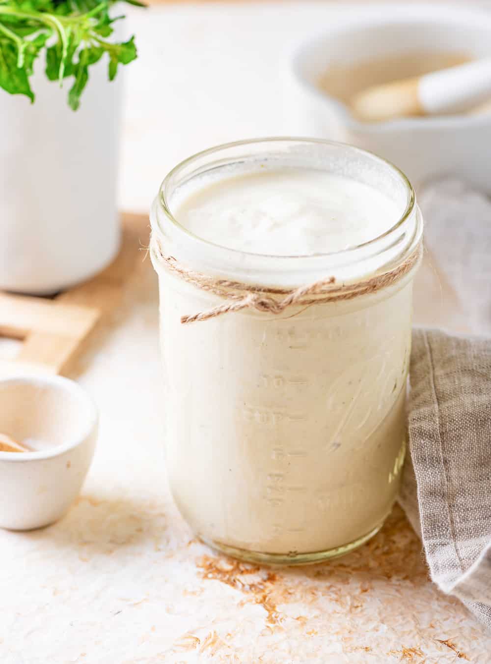 Alfredo sauce in a mason jar that's set on a white table.