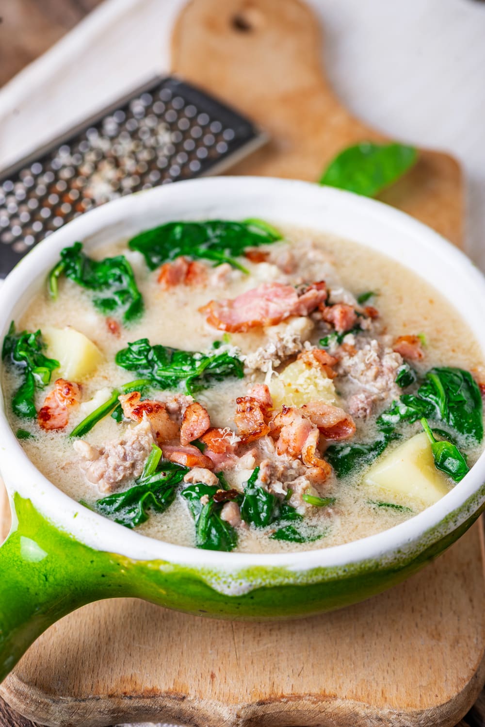 Soup with sausage, greens, and kohlrabi in a green soup bowl.