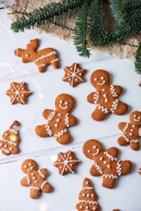 Gingerbread cookies on a white table, with green pine branches above them.