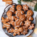 A grey plate with gingerbread cookies on it. Green pine branches are above the plate.
