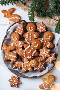 A grey plate with gingerbread cookies on it. Green pine branches are above the plate.