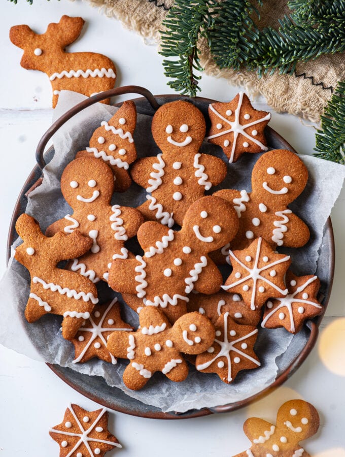 A grey plate with gingerbread cookies on it. Green pine branches are above the plate.