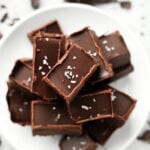 Pieces of chocolate fudge stacked on top of one another on a white plate.