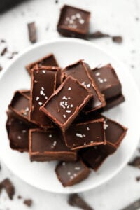 Pieces of chocolate fudge stacked on top of one another on a white plate.