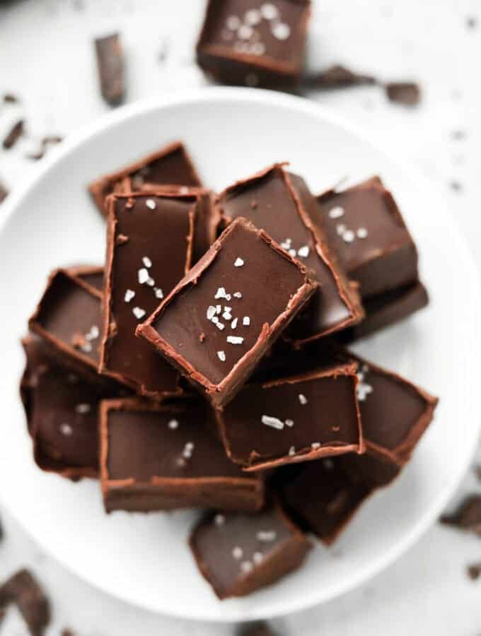 Pieces of chocolate fudge stacked on top of one another on a white plate.