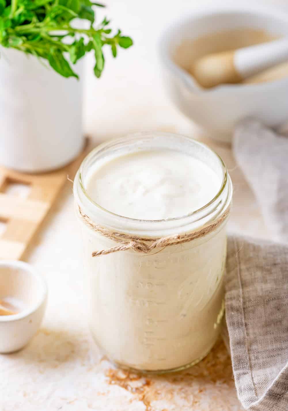 A mason jar filled with alfredo sauce, the jar is on a table.