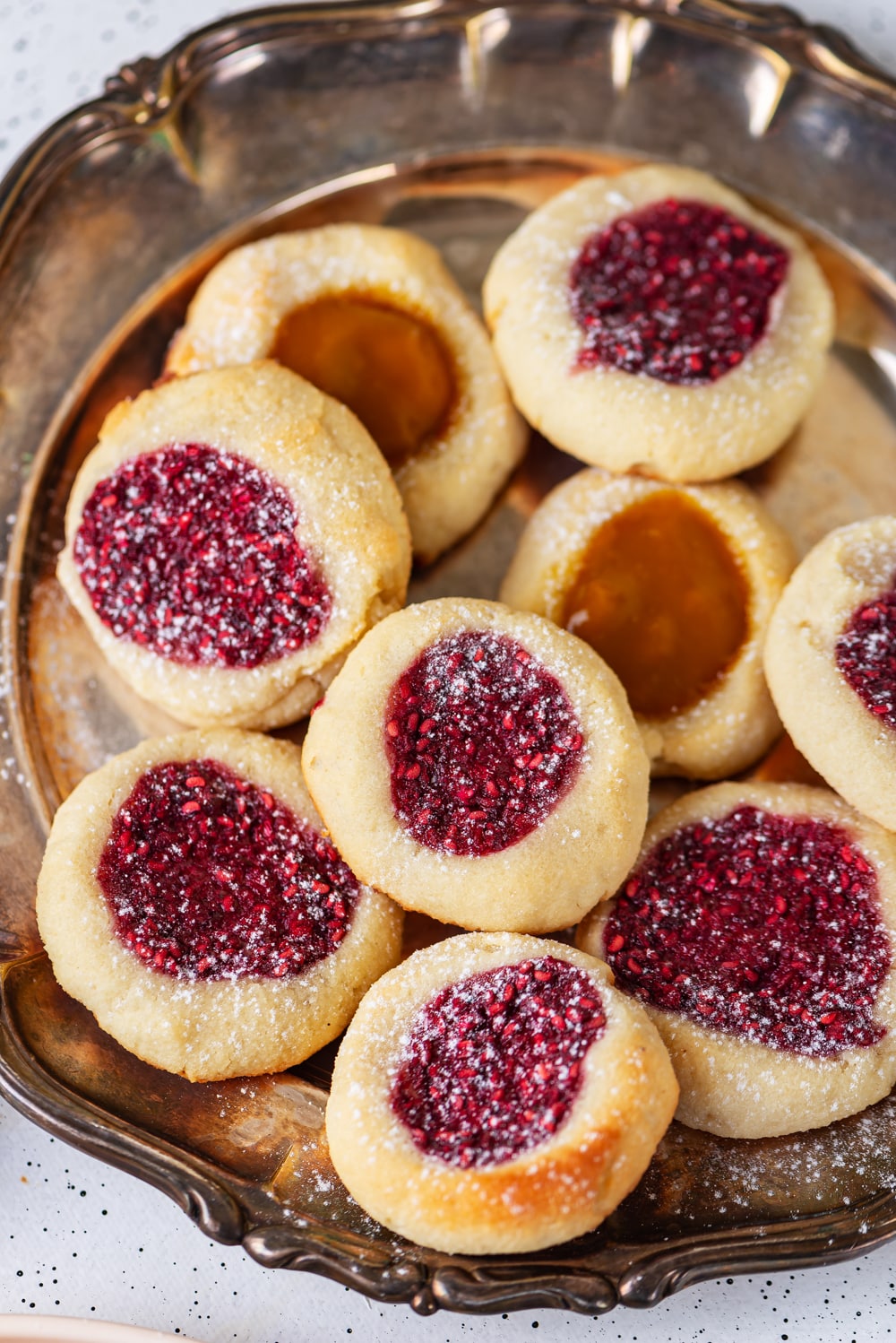 An assortment of jam filled cookies on a silver plate.