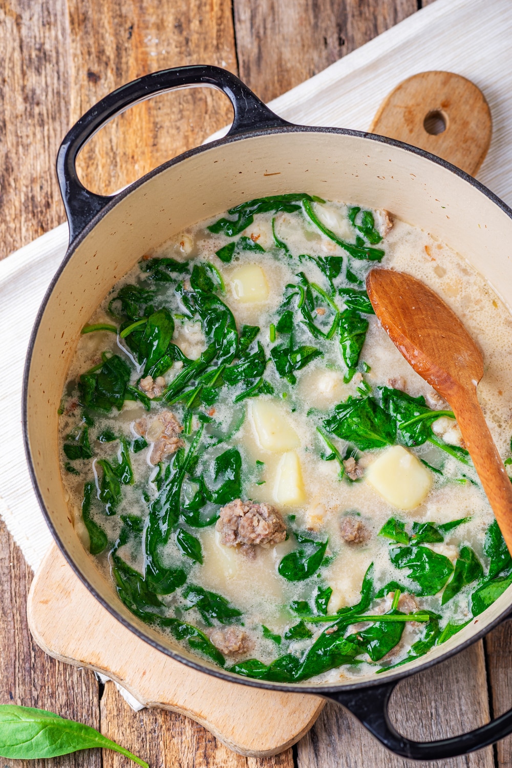 Soup in a black pot. The soup has greens, sausage, and kohlrabi in it.