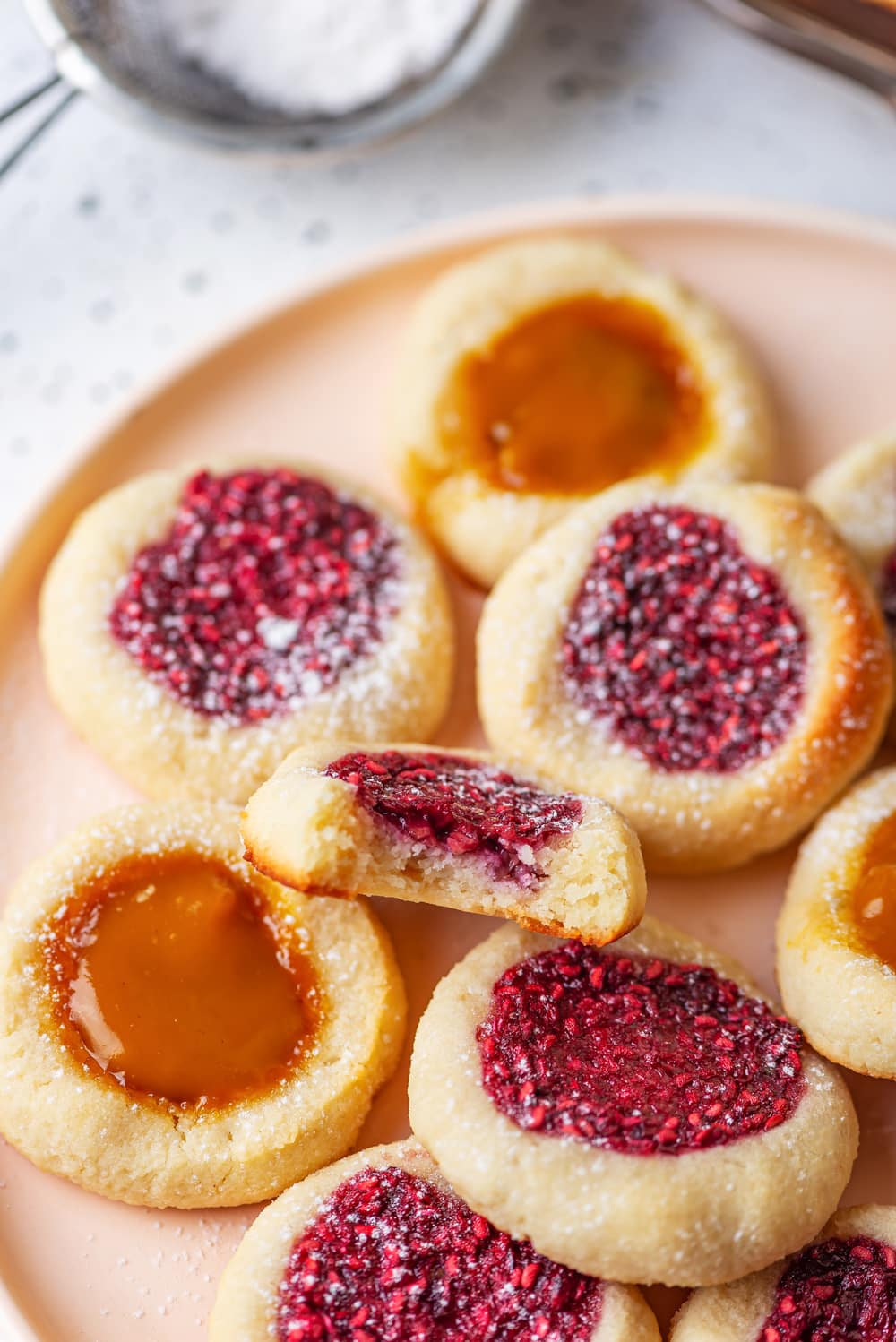 Cookies on a nude colored plate. One of the cookies is sticking up, and has a bite taken out of it.