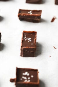 Pieces of chocolate fudge arranged in a row, on a white sheet of paper.