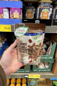 A hand holding a package of mixed nuts.