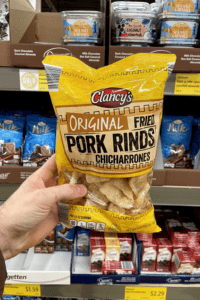 A hand holding a bag of pork rinds.