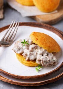 A biscuit filled with gravy on top of a plate that is stacked on top of another plate.