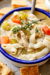 Chicken noodle soup in a white bowl with a blue colored rim.