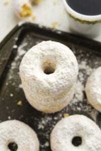 3 Donuts staked on top of one another on a baking tray.