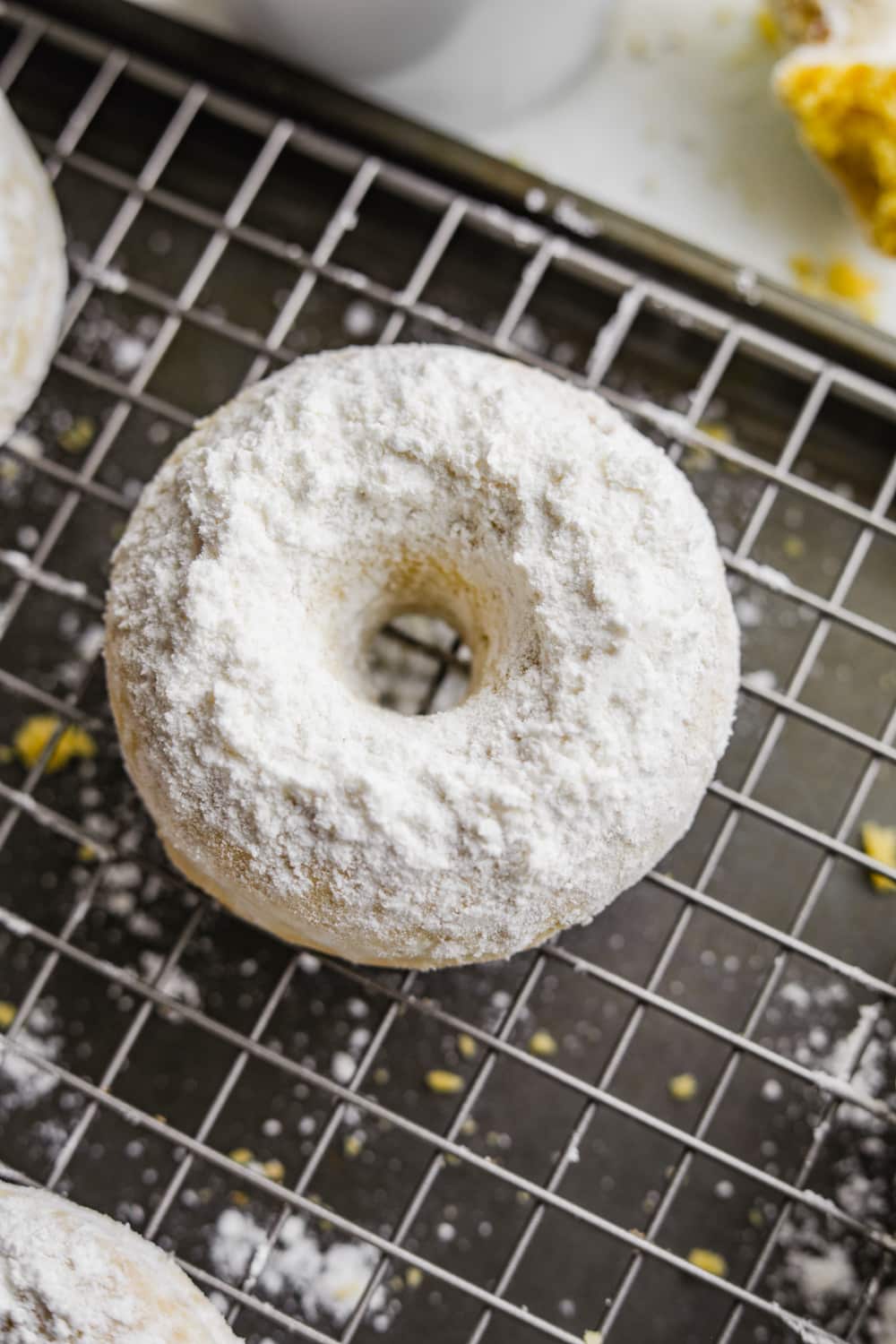 A donut on a wire rack covered in powdered sugar