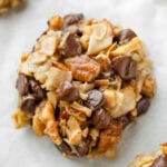 A cookie that has pieces of coconut, pecans, and chocolate chips in it.