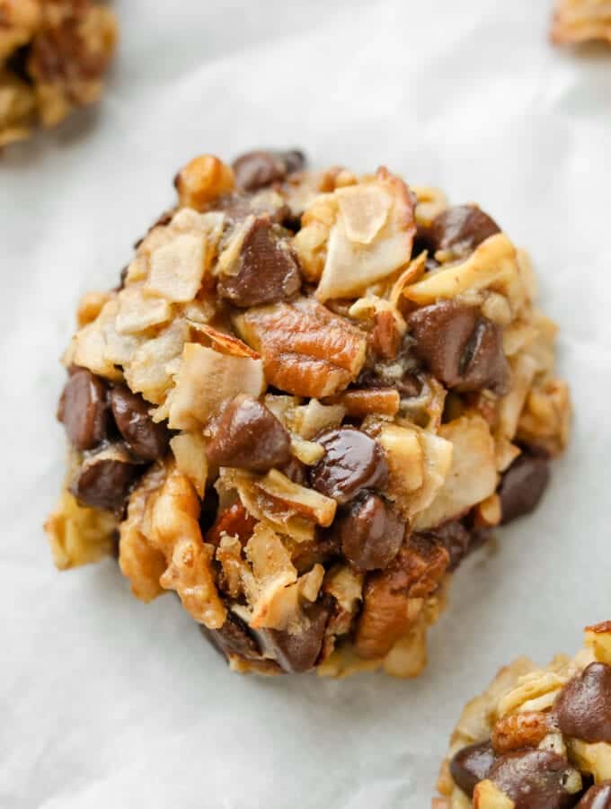 A cookie that has pieces of coconut, pecans, and chocolate chips in it.