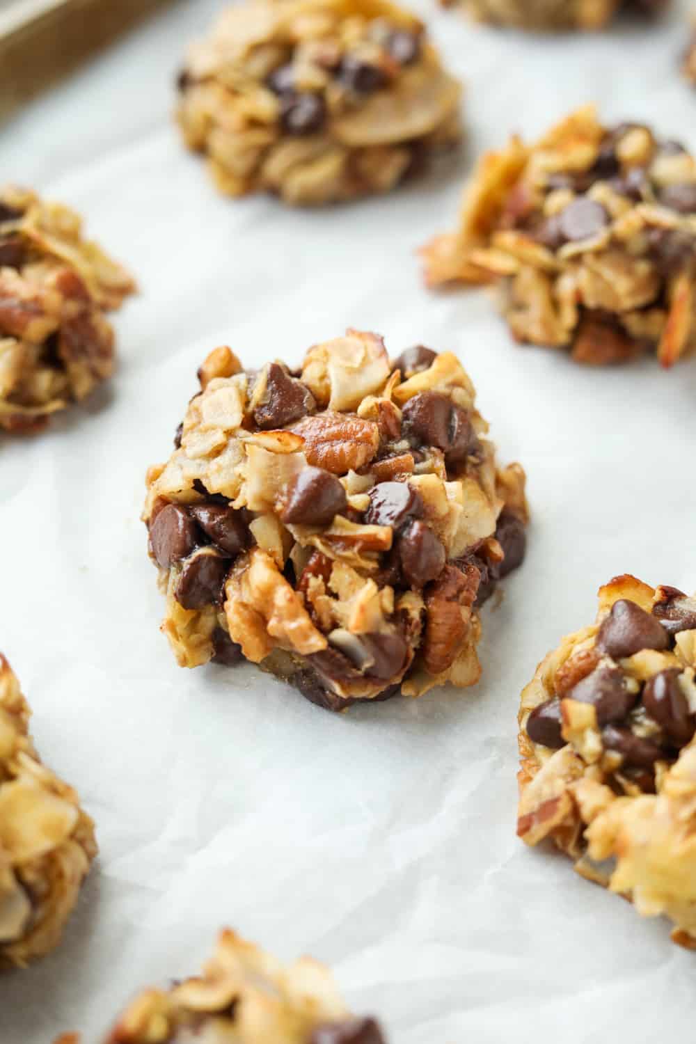 A cookie on a white sheet of parchment paper with other cookies next to it.