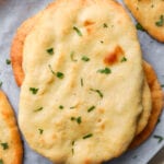 Naan bread on a baking sheet lined with parchment paper.