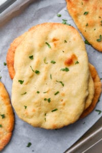 Naan bread on a baking sheet lined with parchment paper.