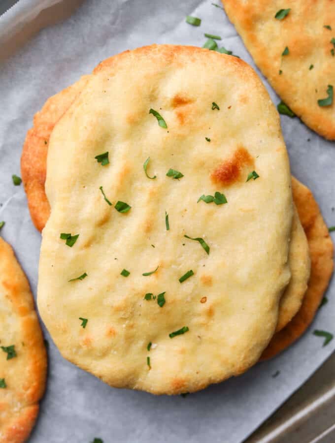 Naan bread on a baking sheet lined with parchment paper.