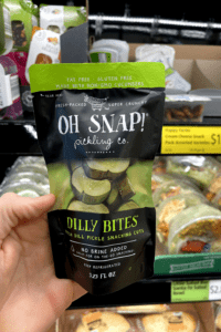 A hand holding a bag of dill pickle bites.