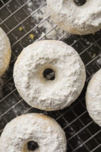 Powdered sugar donuts on a wire rack.