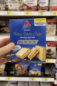 A hand holding a box of keto peanut butter wafer crisps.