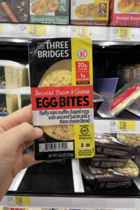 A hand holding a package of bacon and cheese egg bites.